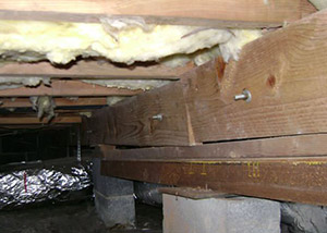 A sagging crawl space with concrete supports and wooden shimming a Manistee crawl space