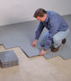 Contractors installing basement subfloor tiles and matting on a concrete basement floor in Muskegon, Michigan & Indiana